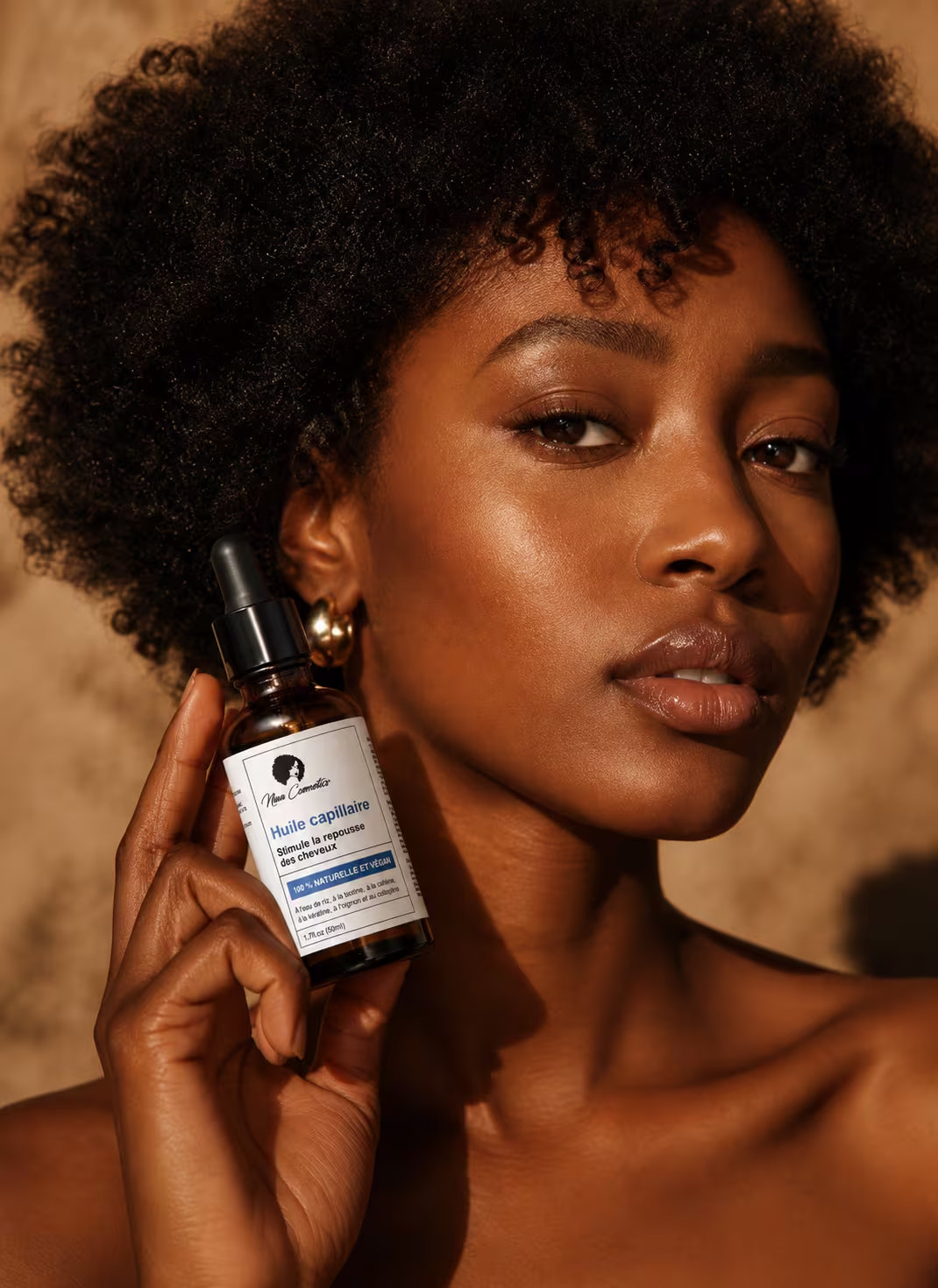 Portrait d'une femme tenant un flacon d'huile capillaire Niwa Cosmetics, lumière dorée naturelle